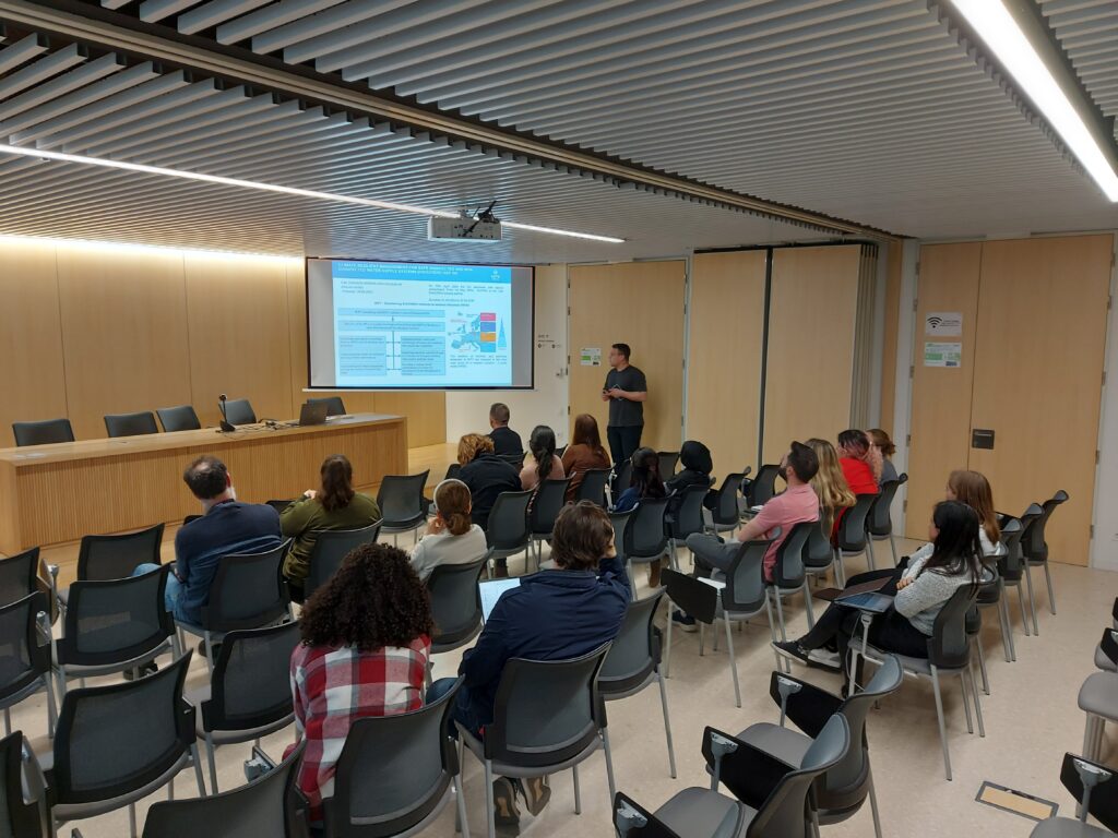 Picture shows a conference room, one man presents SafeCREW case study Tarragona. about 15 people in the audience listening.