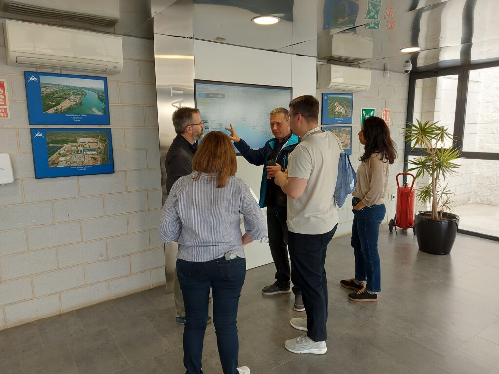 Two women and three men discussing in a foyer. CAT images on the walls.