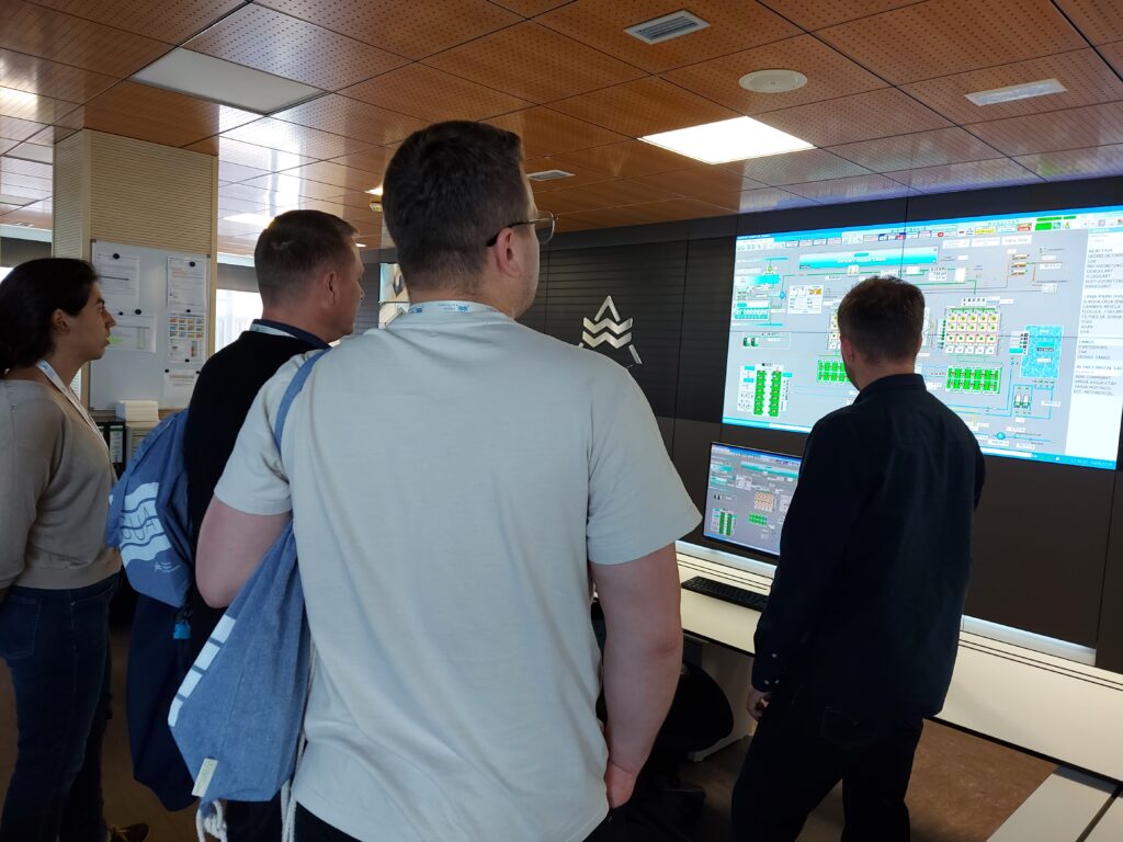 Picture shows three men and one woman looking at the monitoring display of a drinking water treatment plant process.