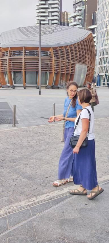 2 women on a place in Milan. In the background a building with a wood facade.