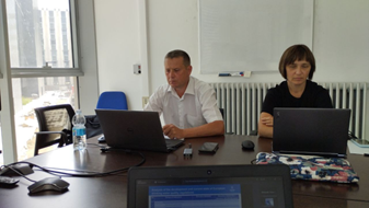 A man and a woman working at their laptops in an office building.